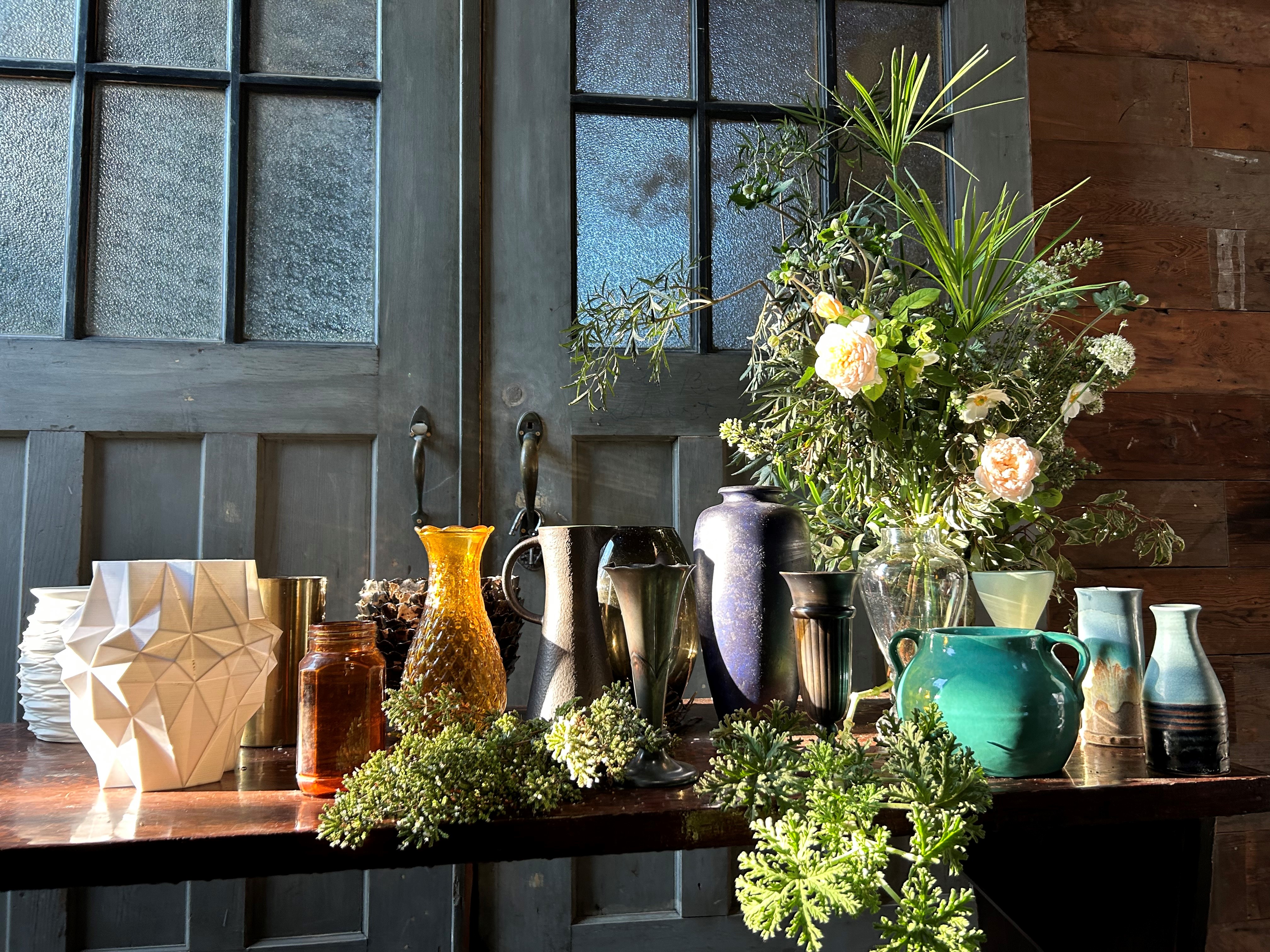 A collection of vases on a shelf ledge, filled with Zinc House Farm flowers