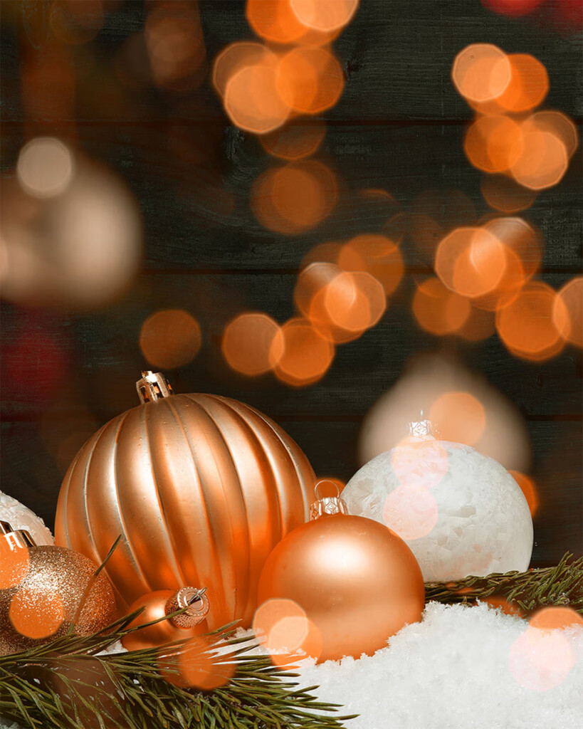 holiday baubles in oranges and white, with wooden wall background and bokeh effect